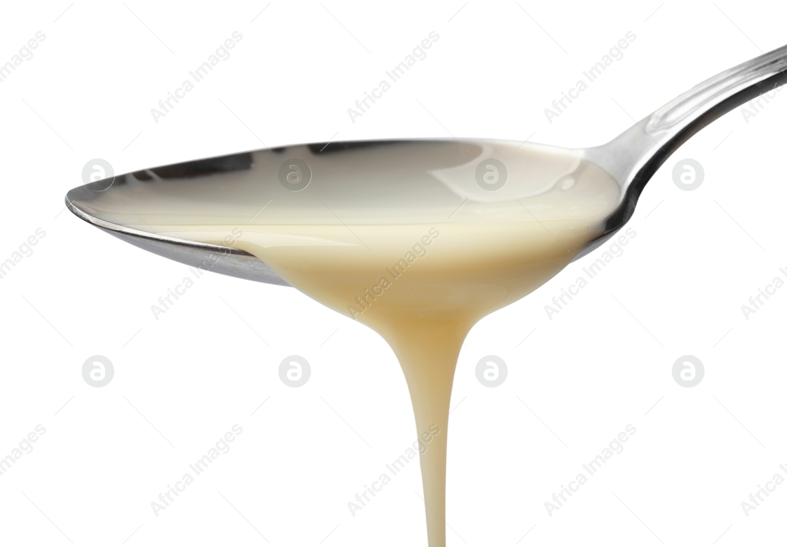 Photo of Delicious condensed milk pouring from spoon isolated on white