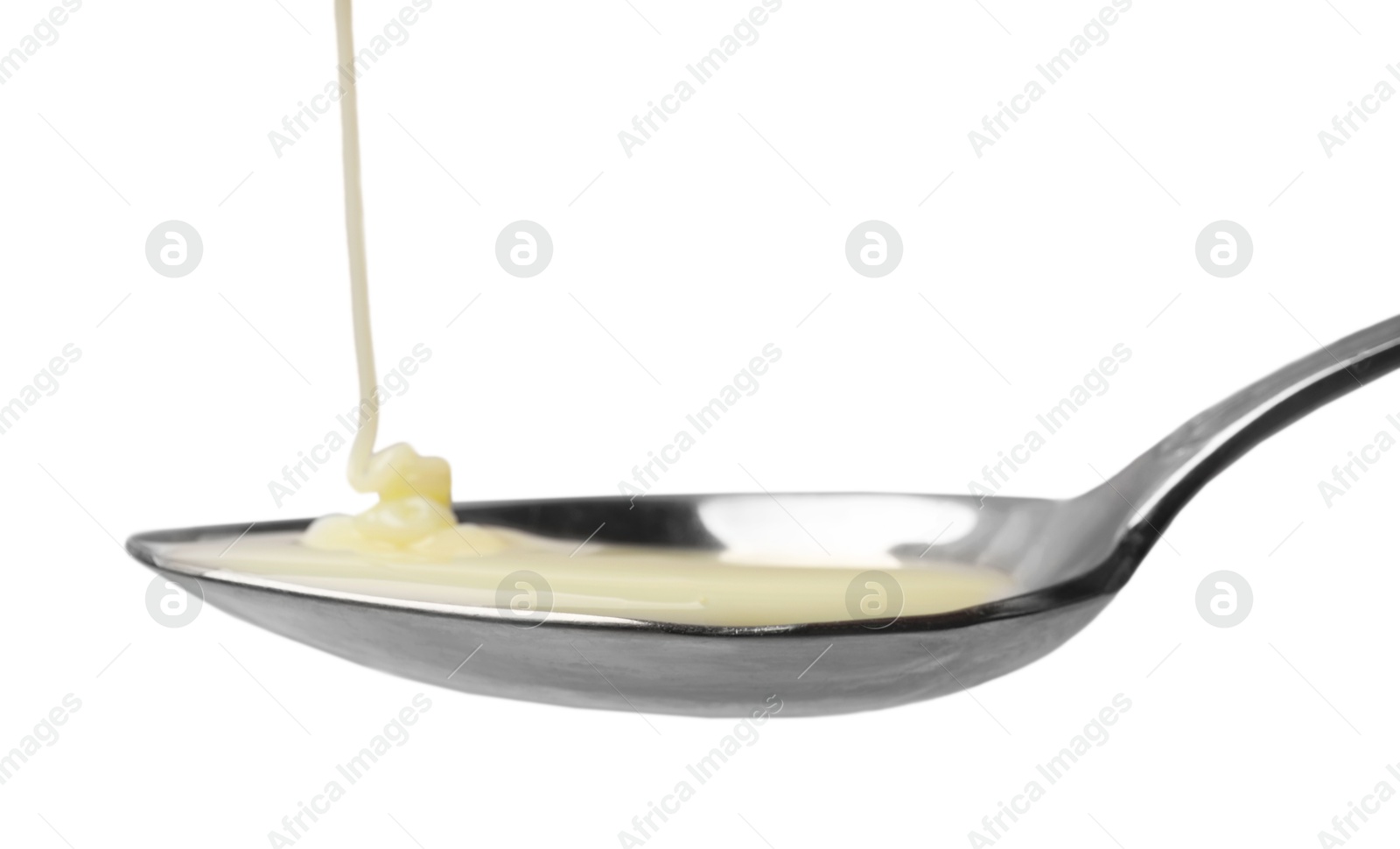 Photo of Delicious condensed milk pouring onto spoon isolated on white