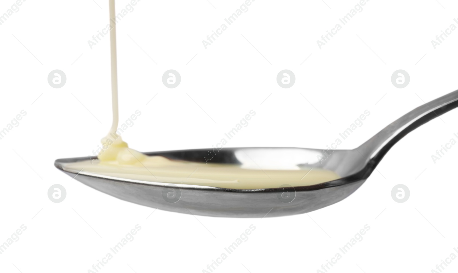 Photo of Delicious condensed milk pouring onto spoon isolated on white