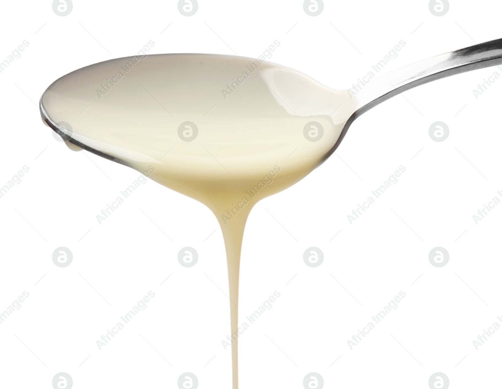 Photo of Delicious condensed milk pouring from spoon isolated on white