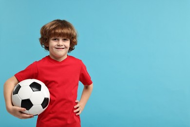 Photo of Little boy with soccer ball on light blue background, space for text