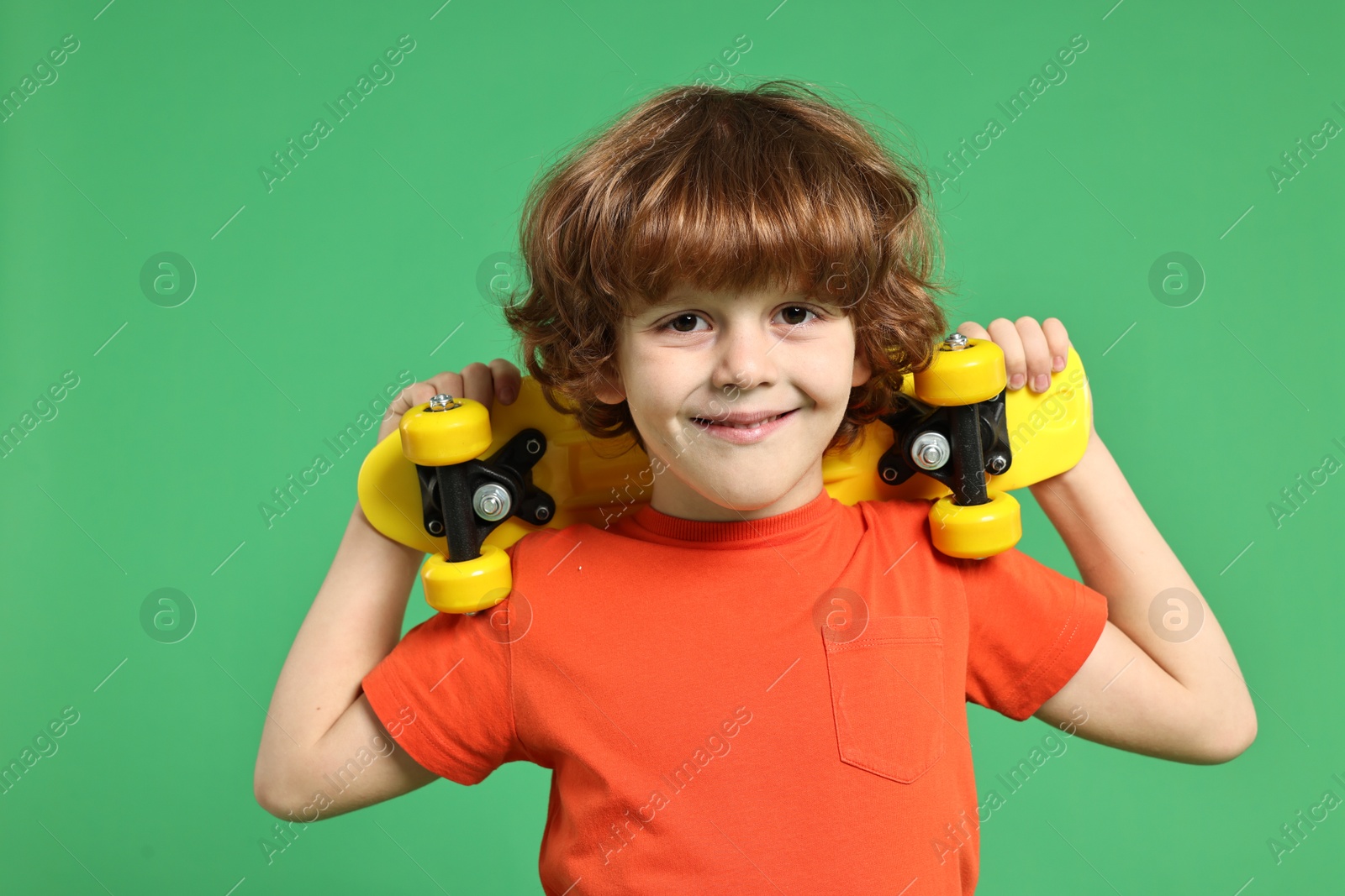 Photo of Little boy with penny board on light green background