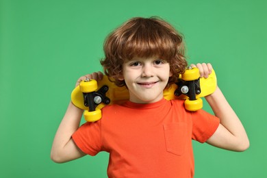 Little boy with penny board on light green background