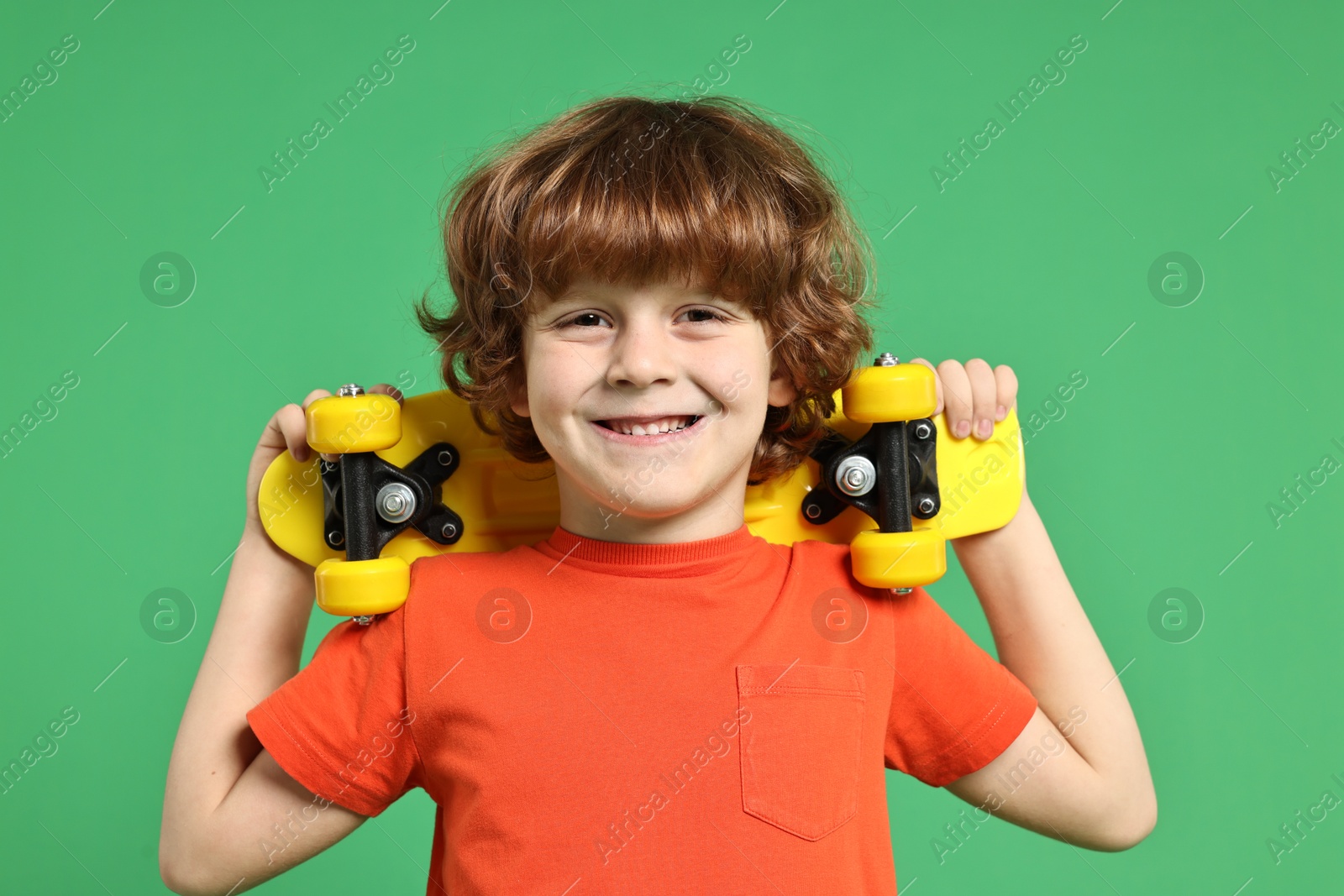 Photo of Little boy with penny board on light green background