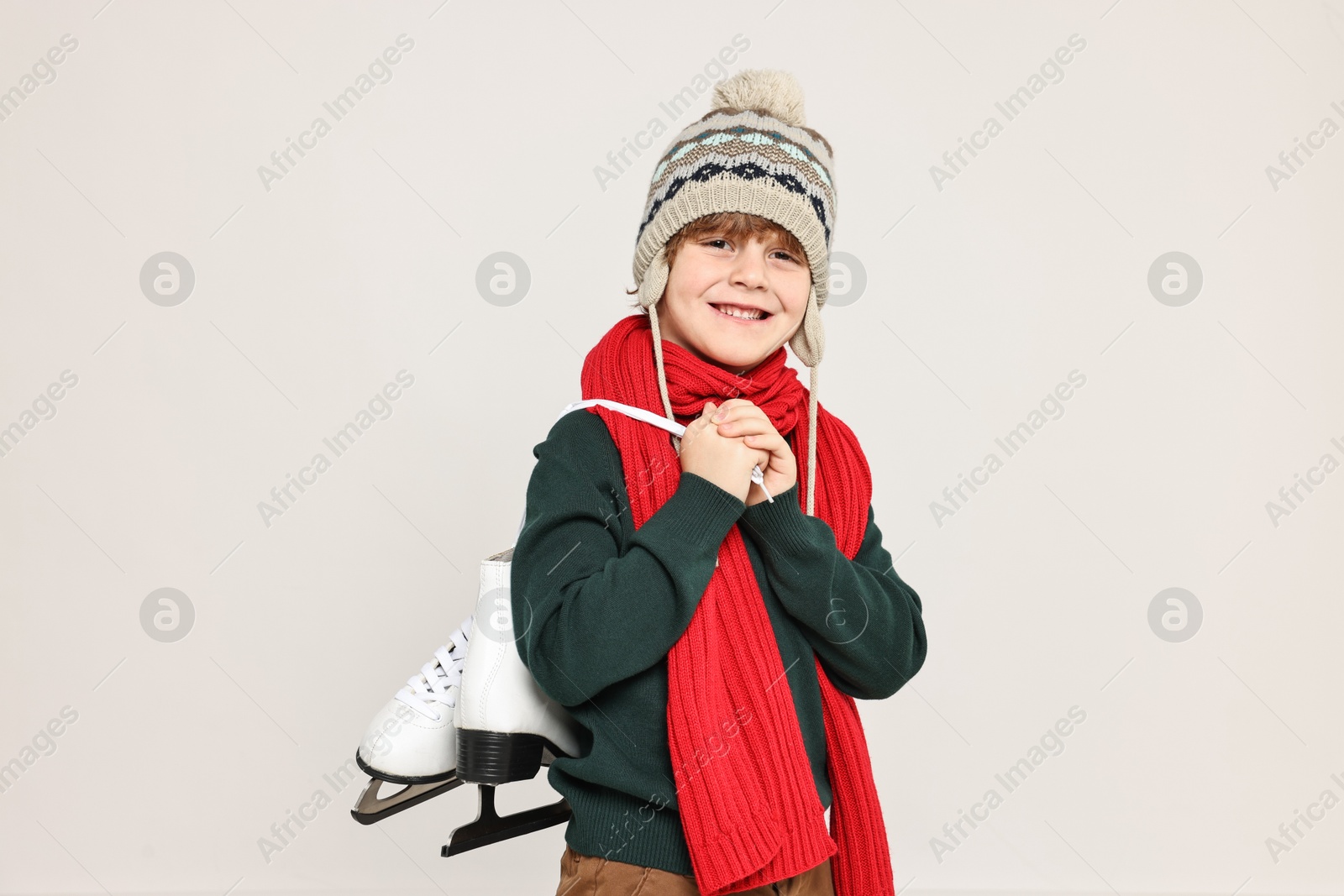 Photo of Little boy in hat with ice skates on light grey background