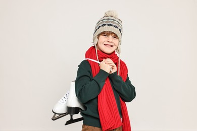 Little boy in hat with ice skates on light grey background