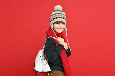 Photo of Little boy in hat with ice skates on red background