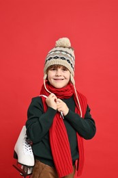 Little boy in hat with ice skates on red background