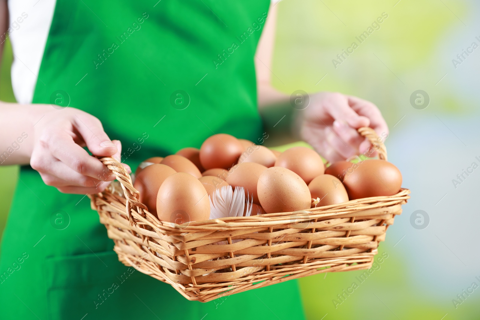 Photo of Woman with basket of eggs on blurred background, closeup