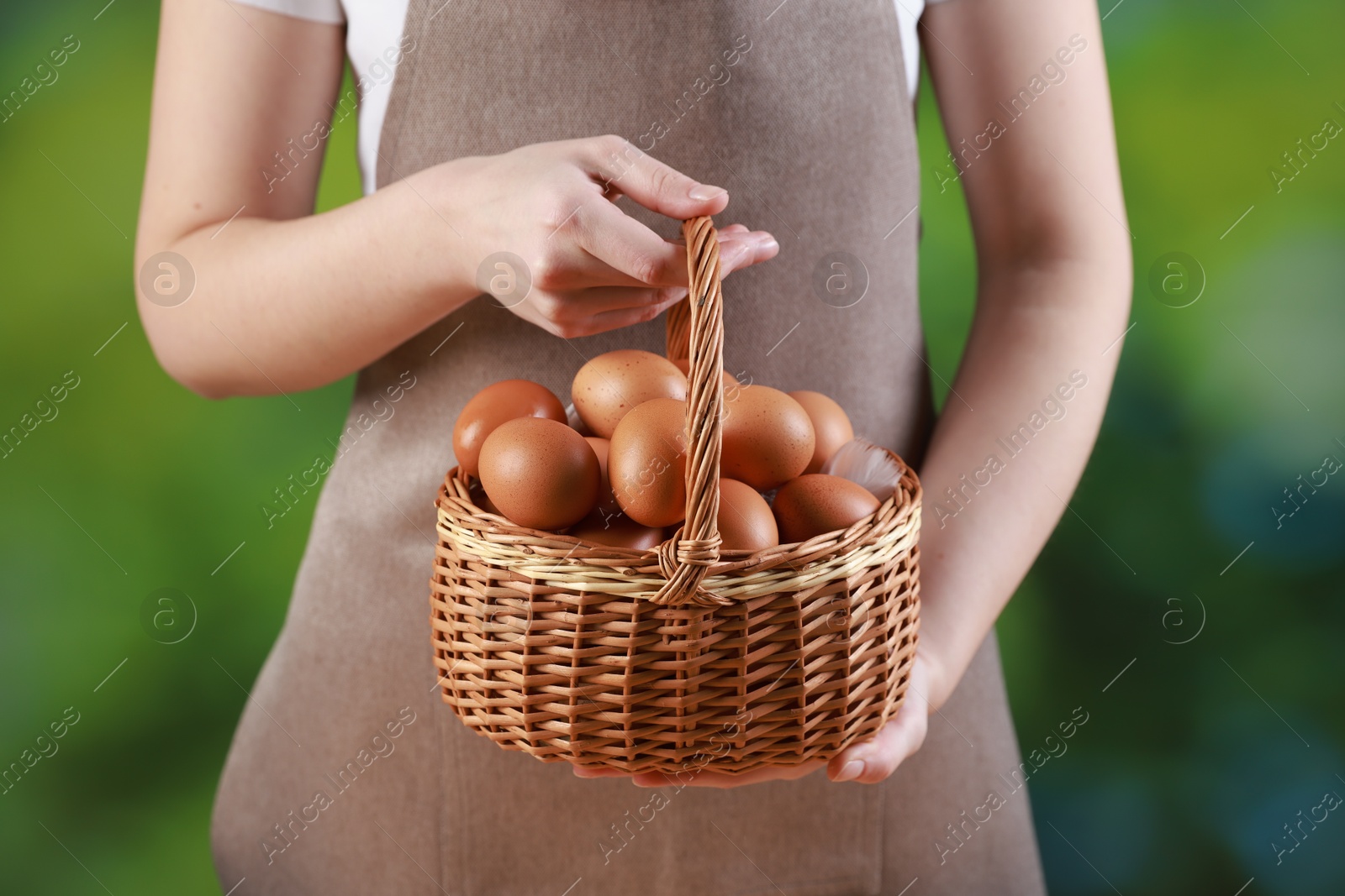 Photo of Woman with basket of eggs on blurred background, closeup