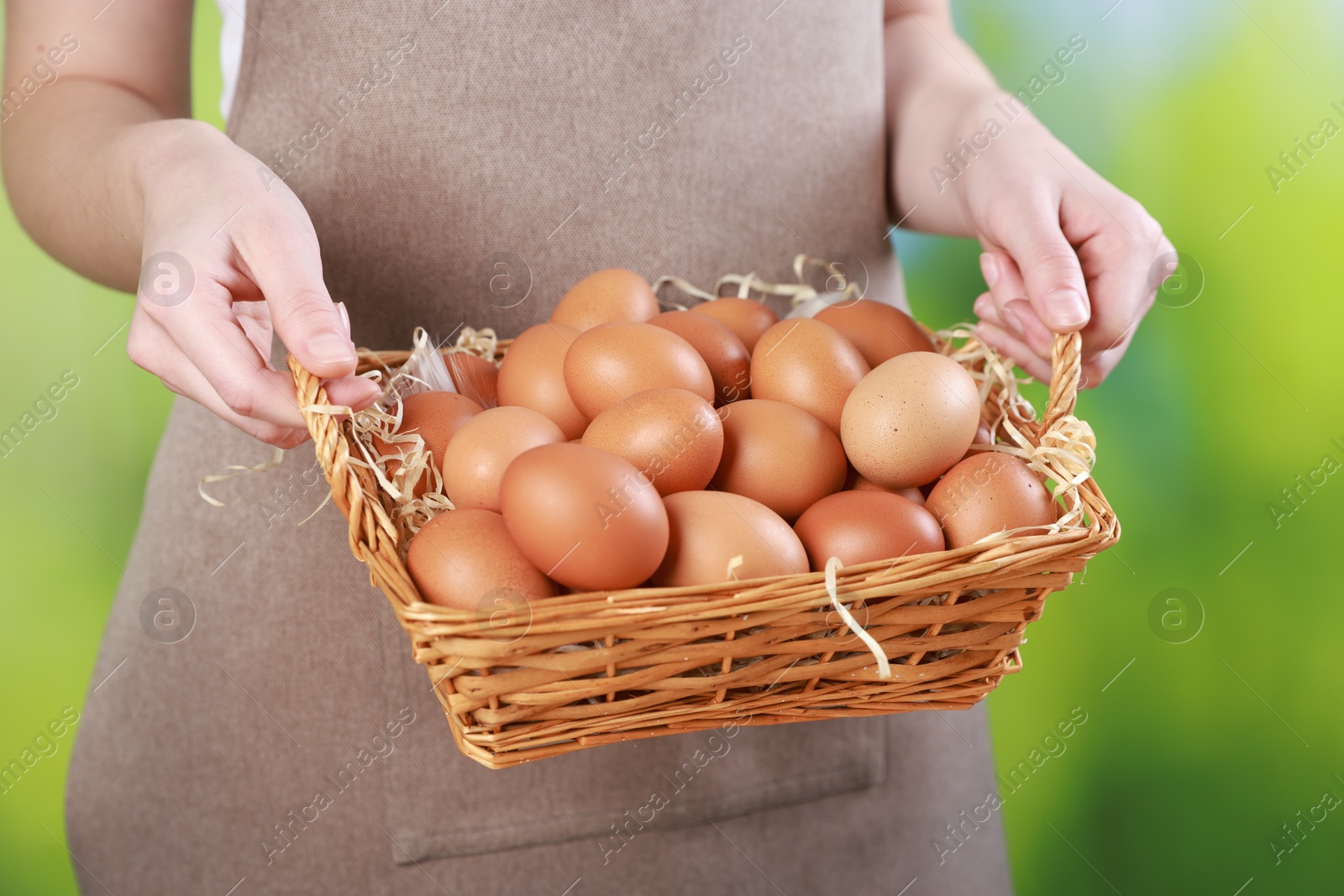 Photo of Woman with basket of eggs on blurred background, closeup