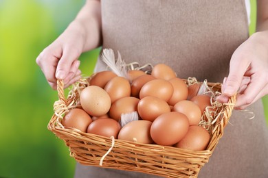 Photo of Woman with basket of eggs on blurred background, closeup