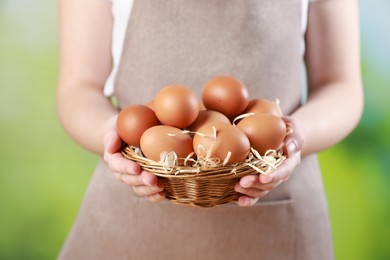 Photo of Woman with basket of eggs on blurred background, closeup