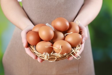 Photo of Woman with basket of eggs on blurred background, closeup