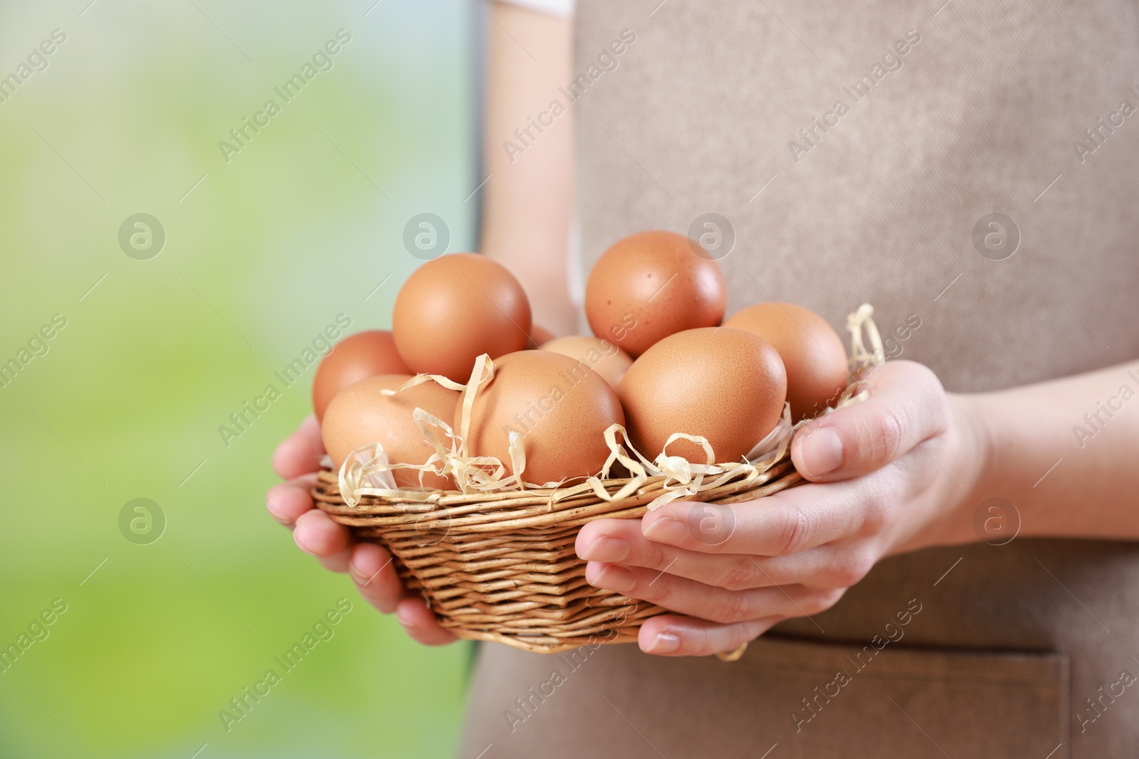 Photo of Woman with basket of eggs on blurred background, closeup. Space for text