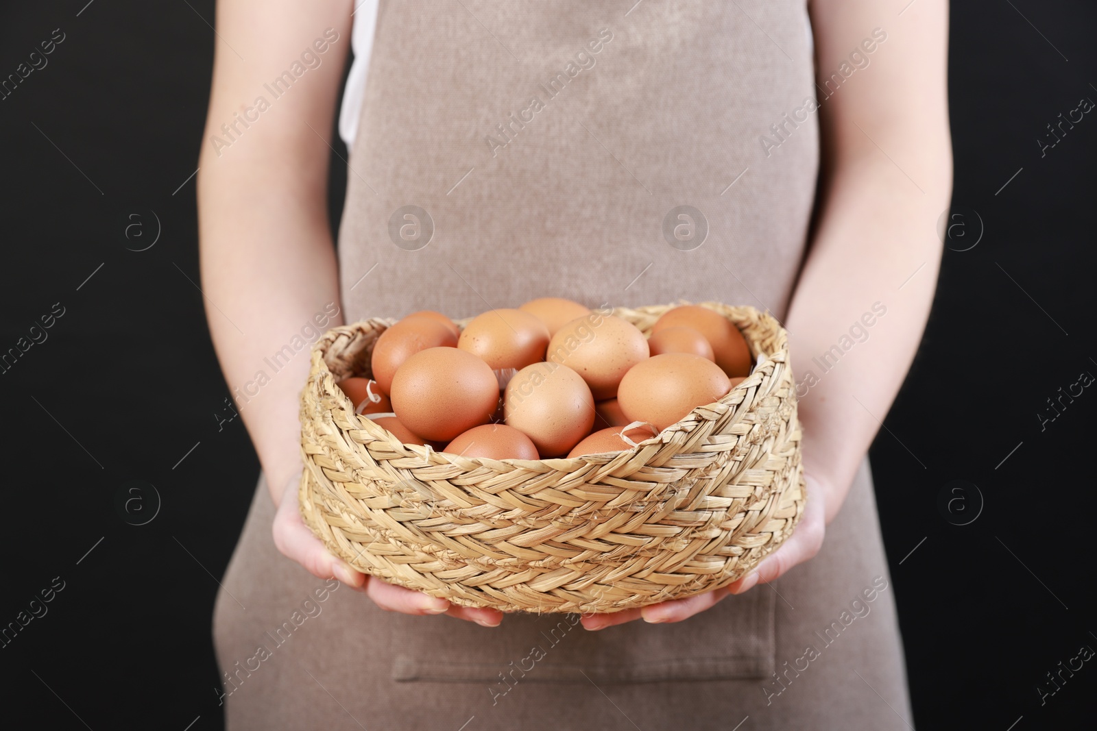 Photo of Woman with basket of eggs on black background, closeup