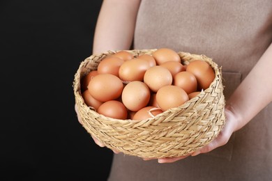 Photo of Woman with basket of eggs on black background, closeup