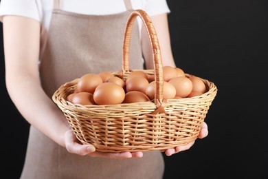 Photo of Woman with basket of eggs on black background, closeup