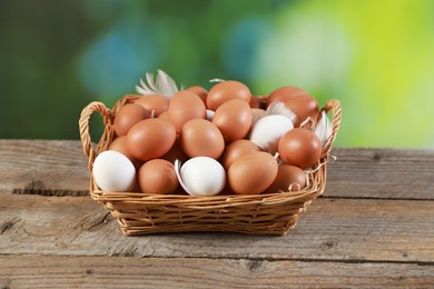 Photo of Many raw eggs in basket on wooden table, closeup