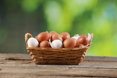 Photo of Many raw eggs in basket on wooden table