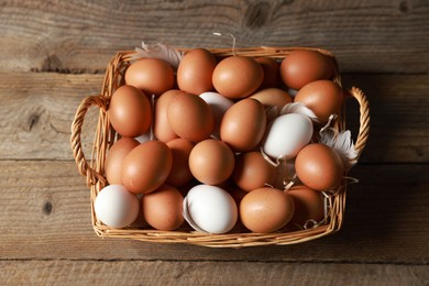 Photo of Many raw eggs in basket on wooden table, above view