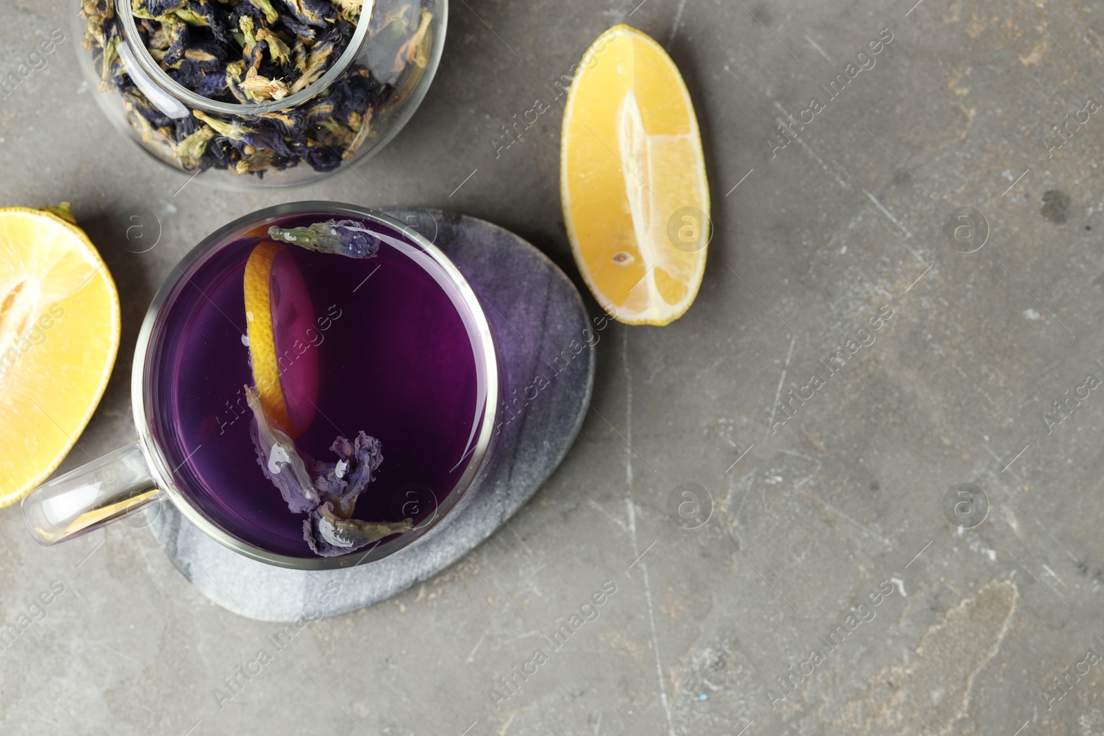 Photo of Delicious butterfly pea flower tea with lemon on gray textured table, flat lay. Space for text