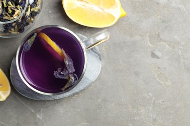 Photo of Delicious butterfly pea flower tea with lemon on gray textured table, flat lay. Space for text