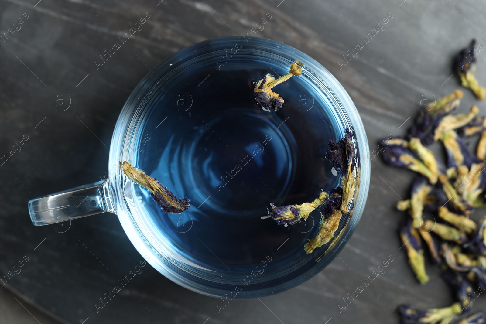 Photo of Delicious butterfly pea flower tea on gray textured table, top view