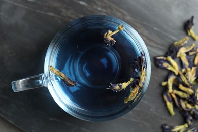 Photo of Delicious butterfly pea flower tea on gray textured table, top view