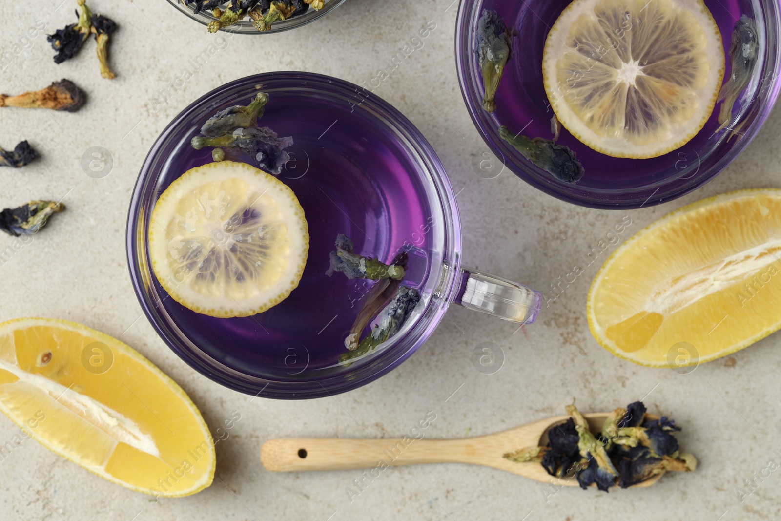 Photo of Delicious butterfly pea flower tea with lemon on gray textured table, flat lay