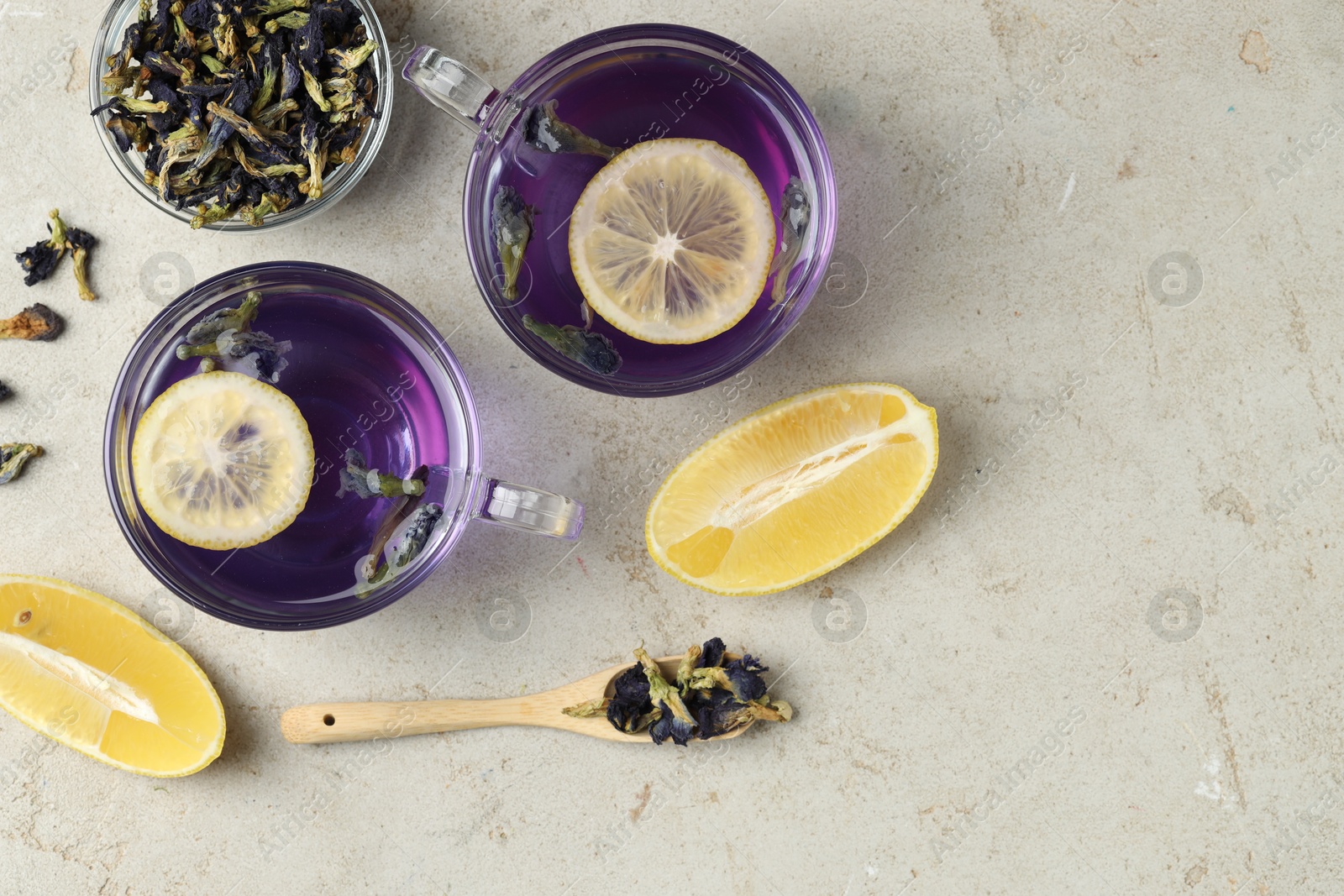 Photo of Delicious butterfly pea flower tea with lemon on gray textured table, flat lay. Space for text