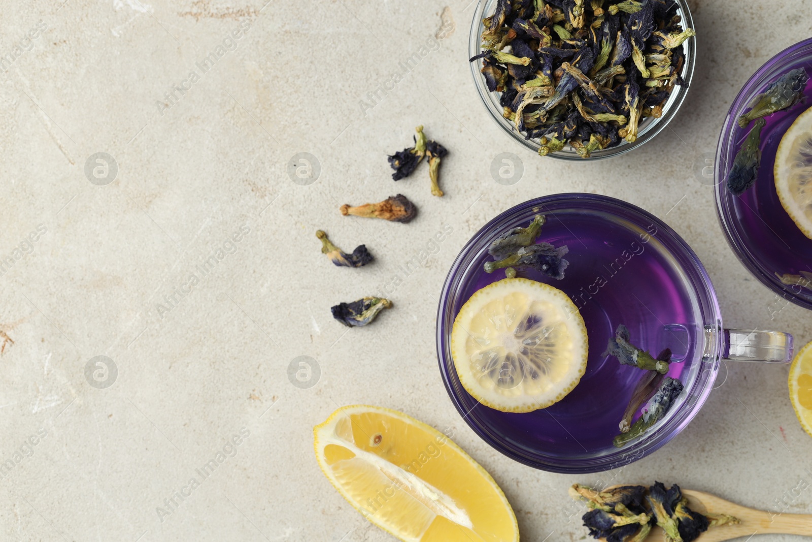 Photo of Delicious butterfly pea flower tea with lemon on gray textured table, flat lay. Space for text