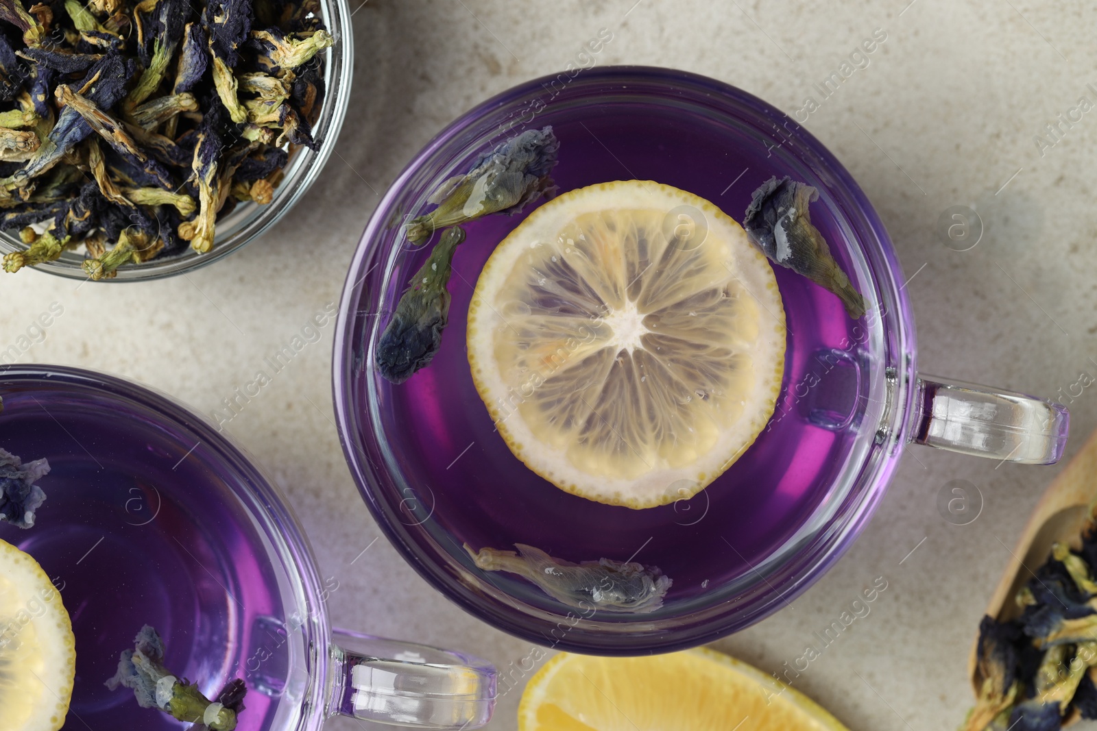 Photo of Delicious butterfly pea flower tea with lemon on gray textured table, flat lay