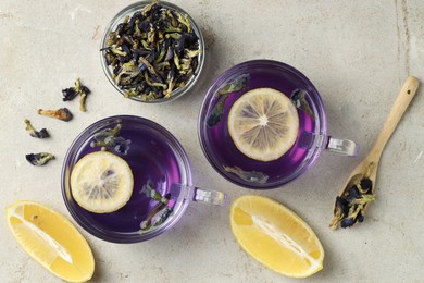 Photo of Delicious butterfly pea flower tea with lemon on gray textured table, flat lay