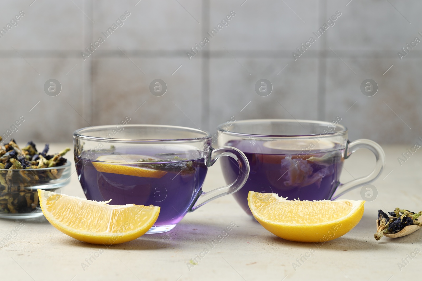 Photo of Delicious butterfly pea flower tea with lemon on gray textured table