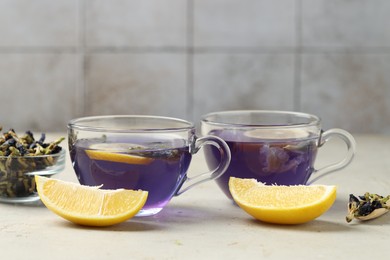 Photo of Delicious butterfly pea flower tea with lemon on gray textured table