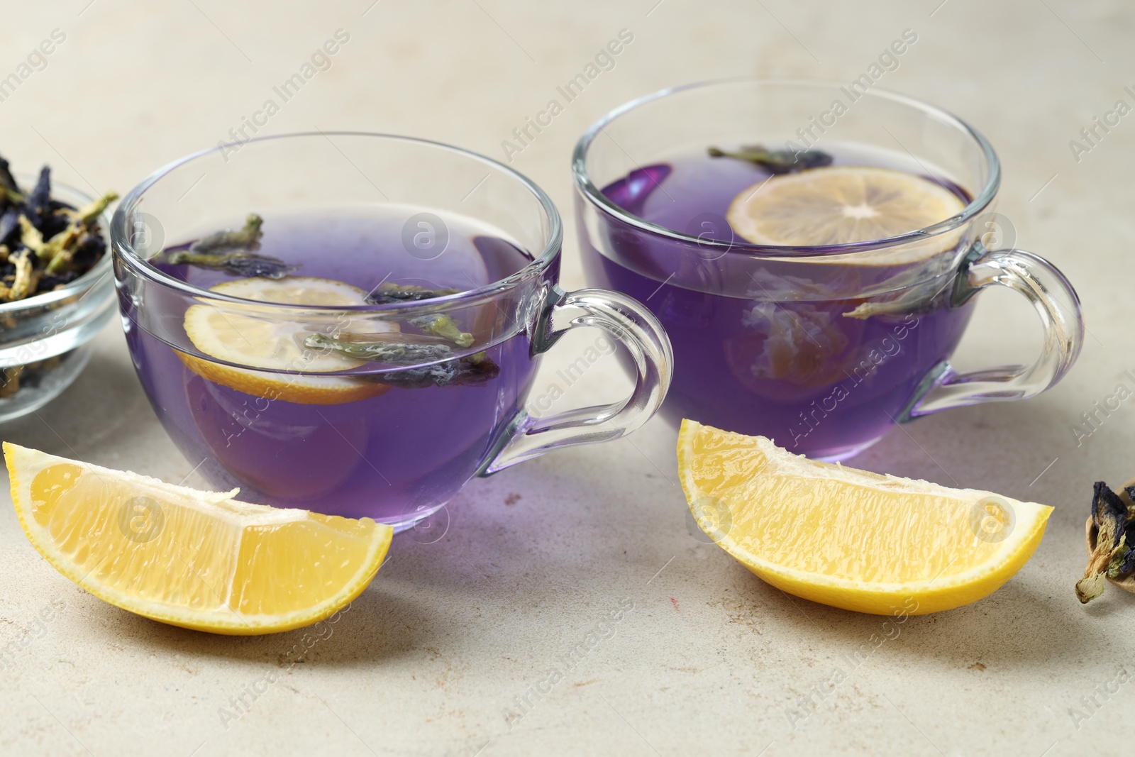 Photo of Delicious butterfly pea flower tea with lemon on gray textured table, closeup