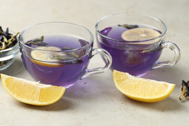 Photo of Delicious butterfly pea flower tea with lemon on gray textured table, closeup