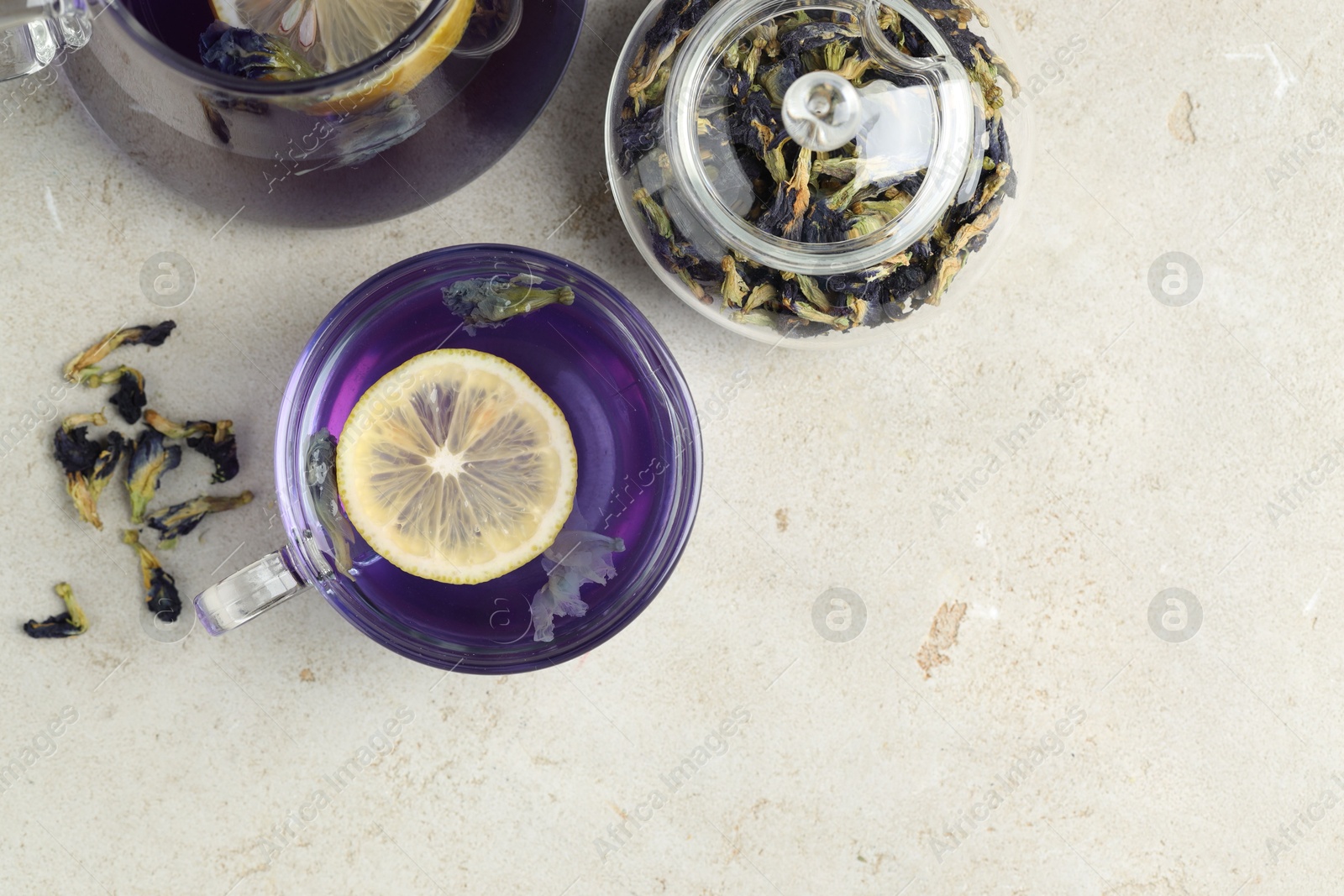 Photo of Delicious butterfly pea flower tea with lemon on gray textured table, flat lay. Space for text