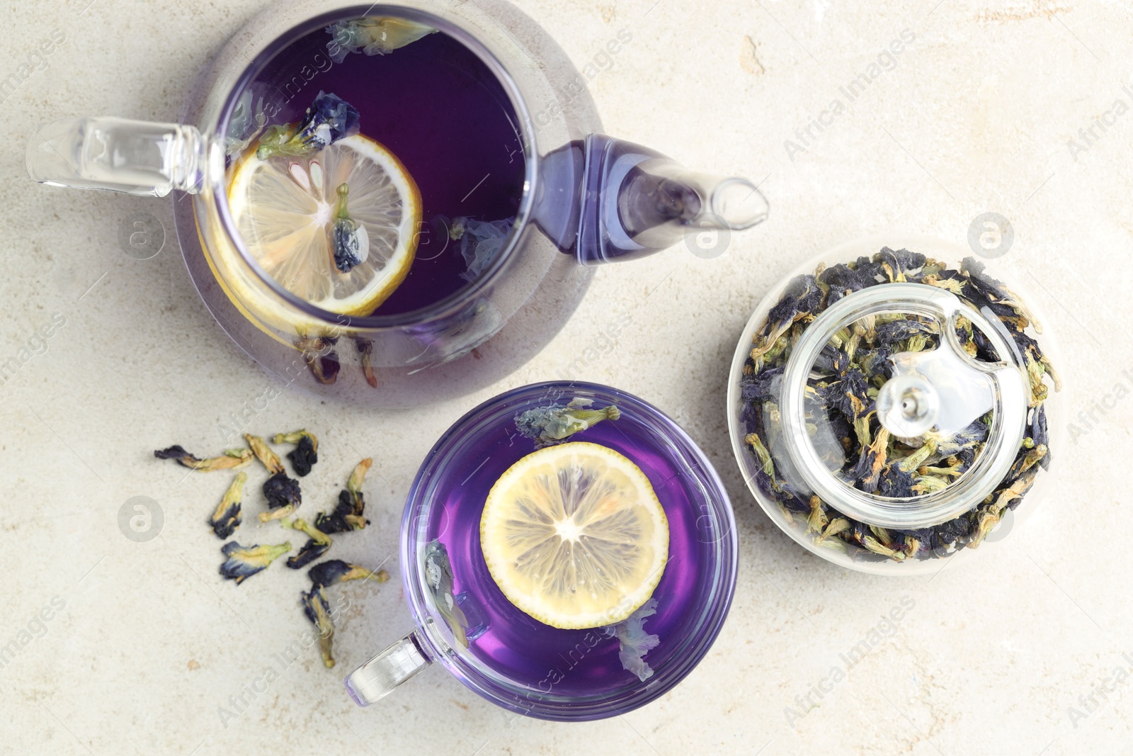 Photo of Delicious butterfly pea flower tea with lemon on gray textured table, flat lay