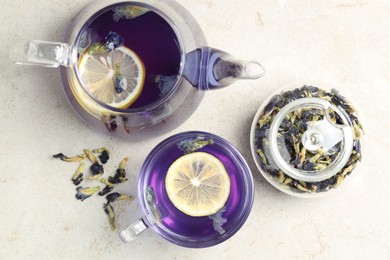 Photo of Delicious butterfly pea flower tea with lemon on gray textured table, flat lay