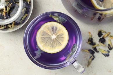 Photo of Delicious butterfly pea flower tea with lemon on gray textured table, flat lay