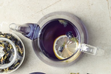 Photo of Delicious butterfly pea flower tea with lemon on gray textured table, flat lay