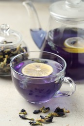 Photo of Delicious butterfly pea flower tea with lemon on gray textured table, closeup