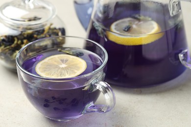 Photo of Delicious butterfly pea flower tea with lemon on gray textured table, closeup