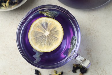 Photo of Delicious butterfly pea flower tea with lemon on gray textured table, top view