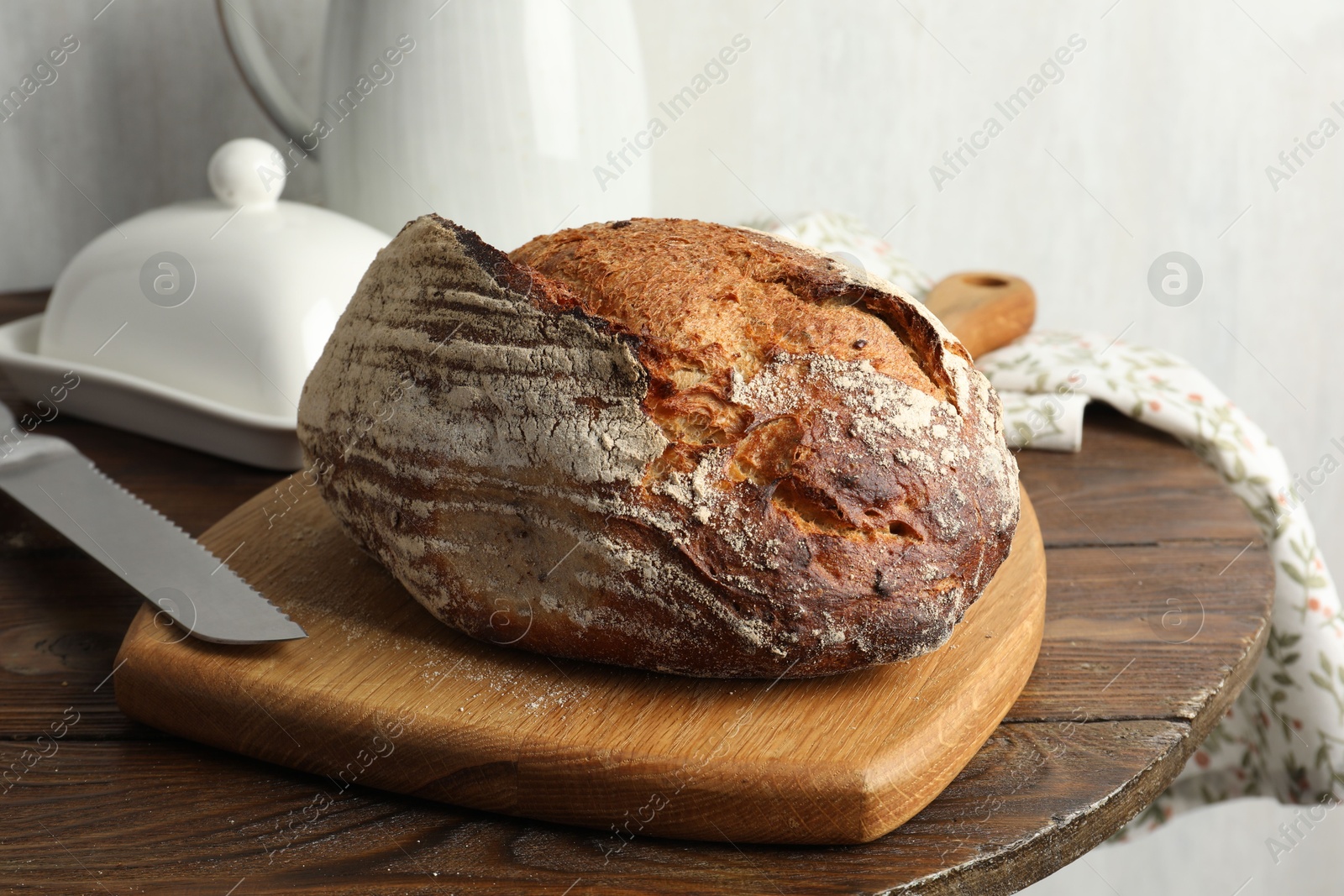 Photo of Freshly baked bread and knife on wooden table, closeup