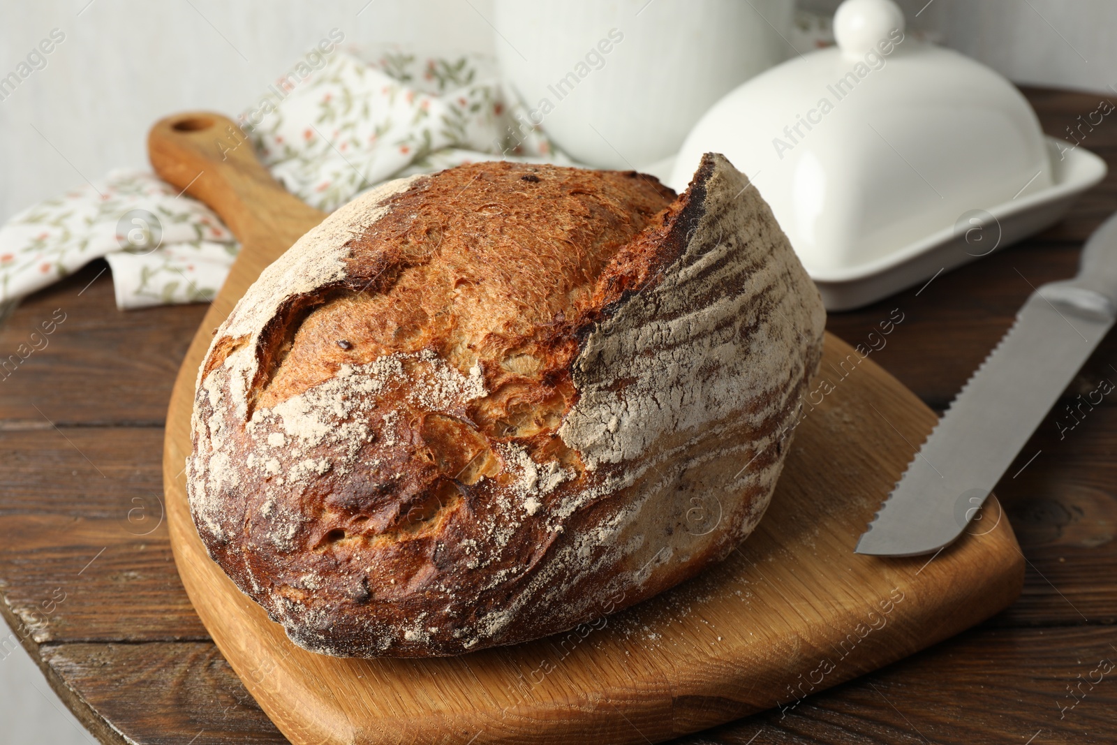 Photo of Freshly baked bread and knife on wooden table, closeup