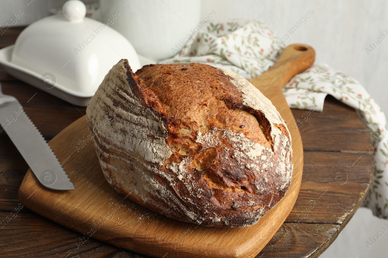 Photo of Freshly baked bread and knife on wooden table, closeup