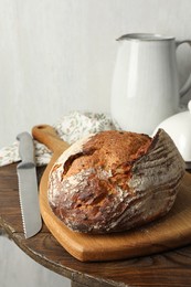 Photo of Freshly baked bread and knife on wooden table, closeup